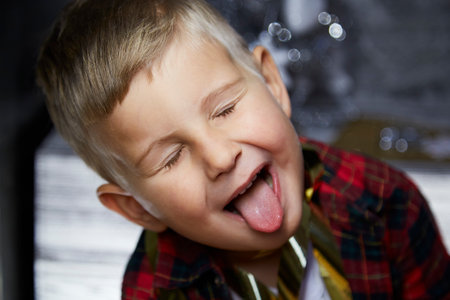 Adorable cheerful child makes a funny face expression close up. Funny baby boy. Joyful cozy home,...
