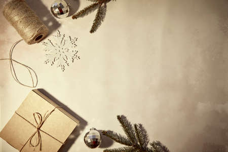 DIY handmade Christmas present. Retro vintage card with crafting decoration, string, branches of fir tree, gift box and trendy ornaments with shadows. Merry Christmas concept. Vignetting, copy space.の写真素材