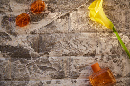Aesthetic style of brick background with orange perfume flacon and sunglasses. Decorations of yellow...