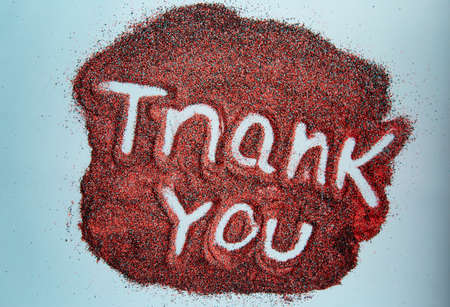 Creative thank you hand written text on red sand surface. Top view. Colorful sandの写真素材