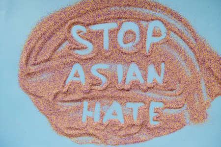 Stop asian hate text handwritten on colorful sand. Actual problem. High quality photoの写真素材