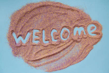 Welcome handwritten text on colorful sand in shape of leaf. Close up. Greeting conceptの写真素材