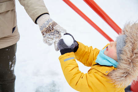 Happy child having fun in the snow. Father and son having fun together. Winter fun outside. Boy in bright orange winter Jacketの写真素材