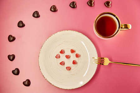 Cute frozen ice hearts on white plate with fork. Chocolate hearts sweets. Creative romantic dinner,...