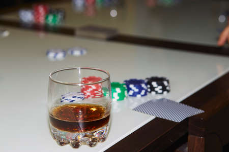 Concept of playing poker on the table with chips and cards. A glass of whiskey. Gambling concept. Copy space. Selective focus.の写真素材