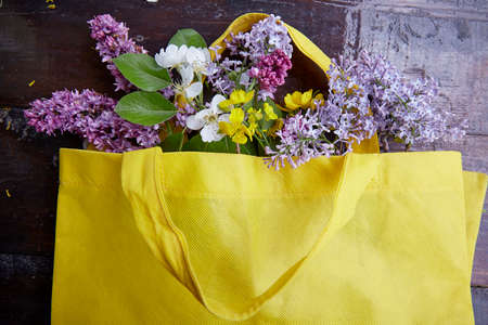 Bouquet of spring lilies, apricot blossoms, blooms in a yellow bag. Sustainable, cottage core, connecting with nature concept.の写真素材