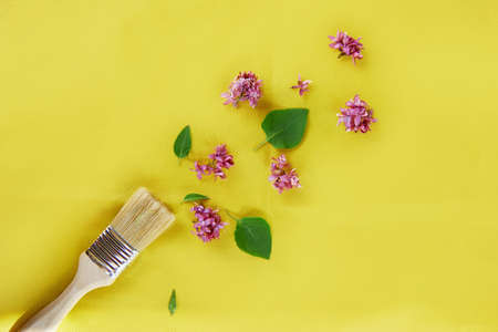 Splash of spring flowers from paint brush on yellow background. Sustainable, cottage core, connecting with nature concept.の写真素材