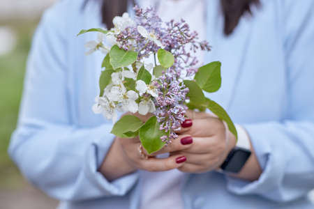 Aesthetic spring flowers in woman's hands close up. Lilac and apricot blooming. spring background.の写真素材
