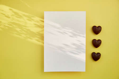Feminine festive post card mock up with shadows, chocolate hearts. Mockup postcard. Copy space.の写真素材