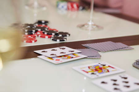 Laying out cards on the table in poker game. Glass of champagne. Gambling concept. Candid moment....