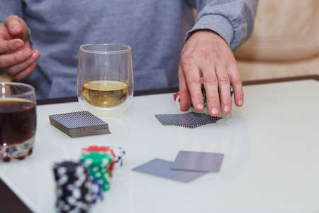 Mans hands shuffle cards. Poker game with chips, cards on the table. Glass of whiskey. Enjoying the moment, digital detox with friends. Lifestyle photography. Candid moment. Selective focusの写真素材