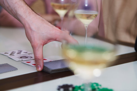 Man's hand in a poker game close up. Chips, cards, glass of champagne on the table with reflection. lifestyle photography. poker club.の写真素材