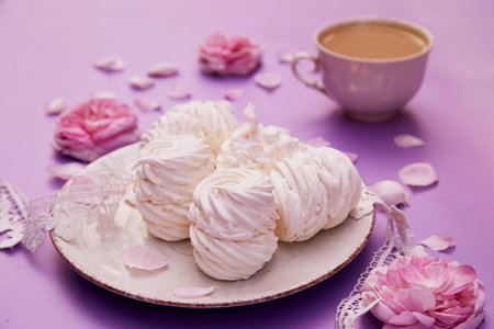 Natural homemade vanilla sugar free marshmallows with cup of coffee. Healthy sweets, natural food. Romantic purple background with tea rose decorations.の写真素材