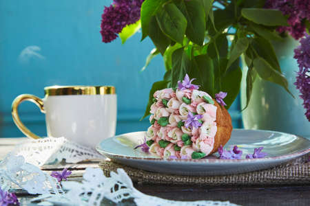 Aesthetic garden picnic with a cup of coffee, beautiful cupcake, flowers and lace decoration. Cottage core picnic with bright summer tones of flowers on a sunny day. hard shadows. breakfast in the gardenの写真素材