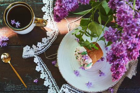 Aesthetic outdoor picnic with a cup of coffee, beautiful cupcake with handmade flowers, flowers and...