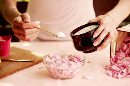 Woman adding sugar to rose petals for natural jam. Aesthetic homemade organic jam preparing with tea rose petals. lifestyle photographyの写真素材