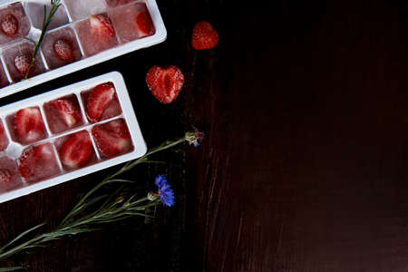 Strawberry ice in the forms. Preparing summer ice for cocktails, ice-cream and desserts. copyspace.