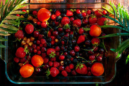 Fresh seasonal fruits and berries: strawberries, apricots, cherries, mulberry, raspberry under...