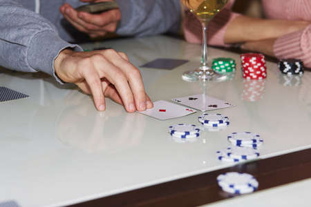 Laying out cards on the table in poker game. Players with dices and cards. Glass of champagne....
