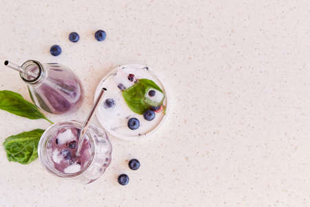Natural herbal organic drink with blueberries, basil extract and leaves, ice under hard shadows. Refreshing soft drink. Copy space.の写真素材