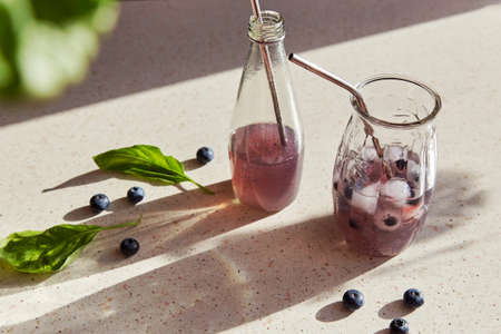 Natural herbal organic drink with blueberries, basil extract, ice under hard shadows. Refreshing soft drink.の写真素材