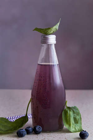 Non-alcoholic healthy organic bottle of drink with blueberries, seeds, basil extract, leaves. Soft...