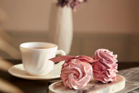Aesthetic tender dessert - marshmallows with currant and cup of black tea. blurred foreground....
