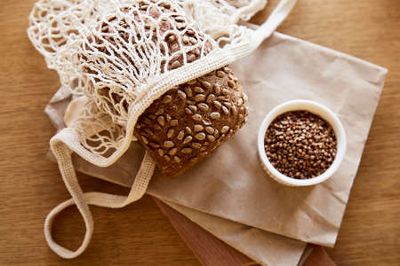 Baked fresh sourdough baguette on newspaper and rustic sacling - traditional french bakery close up....