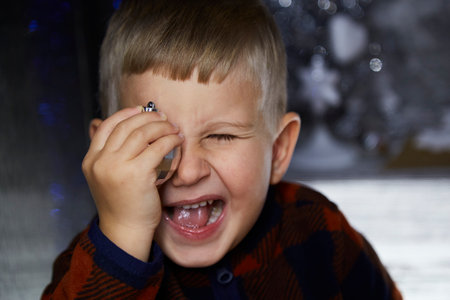 Portrait of cute joyful toddler. Boy plays with christmas tree ball among Christmas decorations. Festive atmospheric home for New Year's Eve. Aesthetic cozy home. Happy baby boy. joyful concept.の写真素材