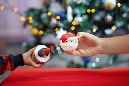 Father and son holding creative festive cupcakes in front of Christmas tree. Cozy Christmas time. Good holidays mood. Selective focusの写真素材