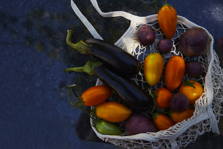 Vegetables in eco shopping bag with tomatoes, eggplant, purple potatoes, under trendy hard shadows...
