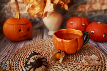 Traditional autumn Halloween cookies and cup of tea among pumpkins.の写真素材