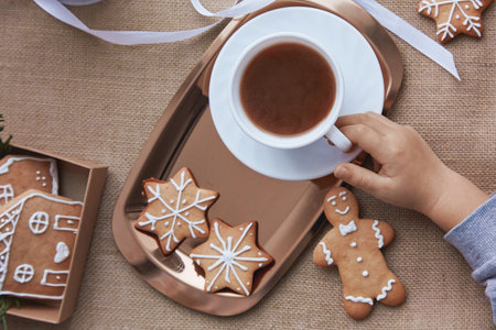 Christmas cozy home. Kid holds cocoa and Christmas gingerbread cookies. Aesthetics winter baking