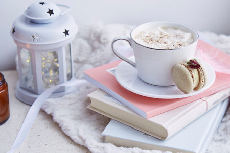 Aesthetics breakfast with hot cocoa and delicate macaroon on the books. Sweet dessert at cozy home.