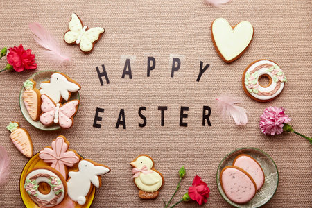 Happy Easter spring pastel background with text. Aesthetic Easter cookies, pink flowers, feathers...
