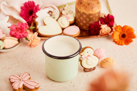 Mug with milk and Easter cake, decorated cookies among flowers. spring cozy aesthetic background