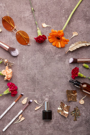 Trendy feminine set with make up brushes accessories, dropper bottles, sunglasses, cosmetics and gerbera flowers with copy space in the centre.の写真素材