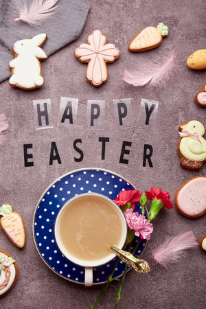 Aesthetic Easter background with text Happy Easter. Stylish decorated Easter cookies, pink flowers, coffee cup and eggs flat layの写真素材