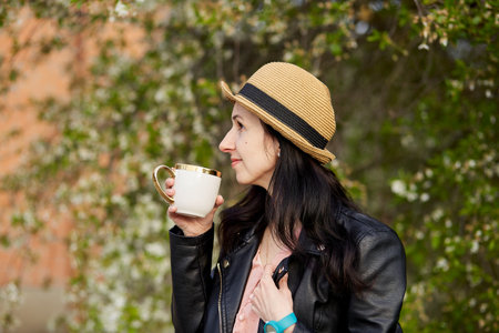 Consciousness, mindful woman with cup of coffee near blooming tree. Life balance, mental life,...