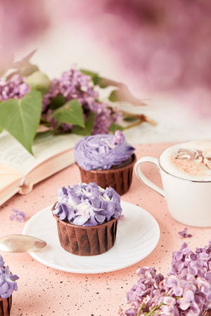 Aesthetic splash background. French purple floral cupcakes using trend Dreamy Escapism with lilac flowers and book. Leisure and relax coffee time.の写真素材