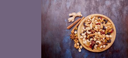 Aesthetic wooden bowl with assorted nuts, raisins and cranberries from above. Hazelnuts, Walnuts, almonds, cashews. Healthy snacks and desserts. Extra wide banner. copyspace.の写真素材