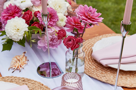 Picnic aesthetics table setting, flowers arrangement, shells. Cozy setup with flowers and candles.の写真素材