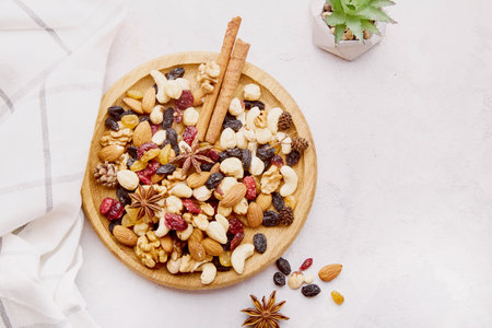 Natural wooden bowl with assortment nuts, raisins and cranberries from above. Aesthetics walnuts, almonds, hazelnuts and cashews. Healthy snacks and desserts.の写真素材