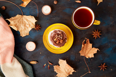 Aesthetic Pavlova cake with Tea Cup. Autumn tea time vibes among leaves. Fall table setting.の写真素材