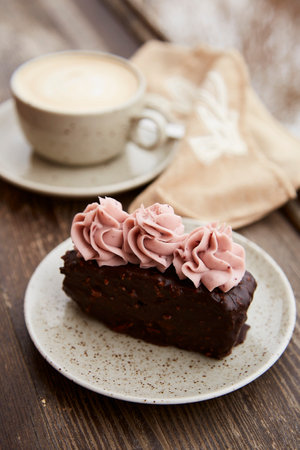 Traditional brownie cake with cup of cappuccino outdoor. Winter aesthetics.