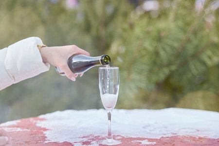 Woman filling glass of champagne outside at Christmas fair. Happy New Year's Eve.の写真素材
