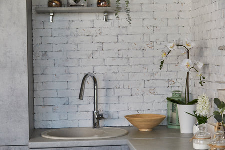 Trendy kitchen design featuring sink and greenery accents. White brick texture.の写真素材