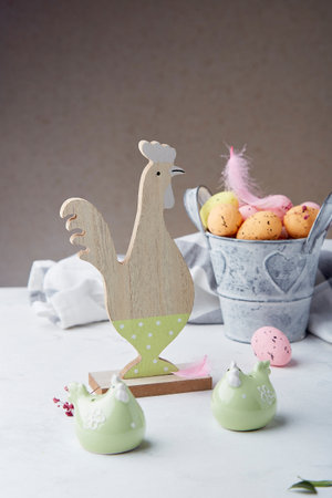 Wooden rooster decoration and ceramic chicken - table setting for Easter holidays.