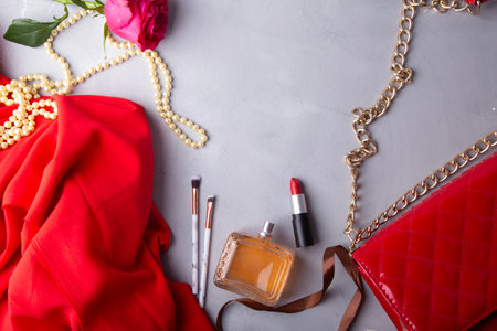 Red essentials with perfume, lipstick and fresh flowers.の写真素材
