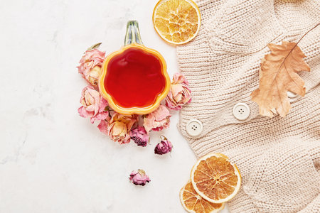 Autumn-Inspired sweater weather background - pumpkin tea cup among dry roses leaves.の写真素材